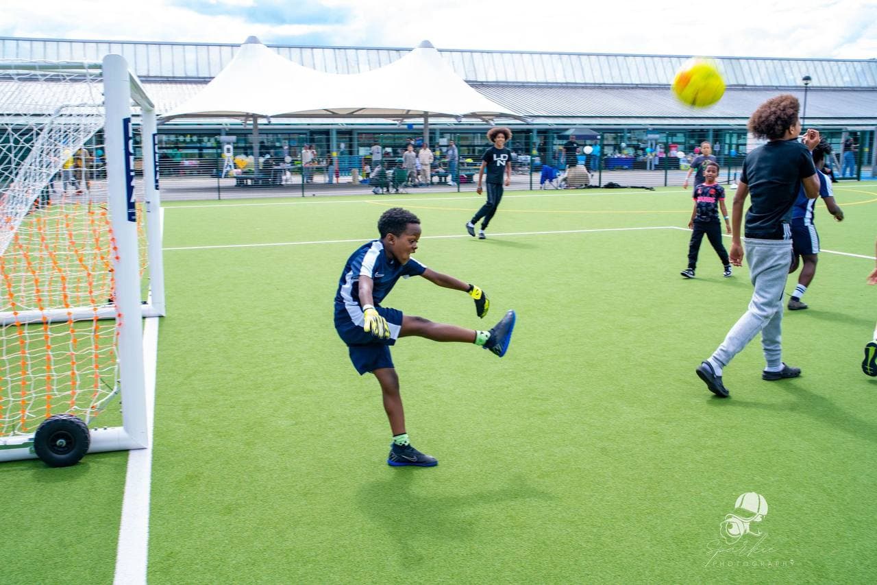 Young goalkeeper practising during Roots & Wings 2024 football activities