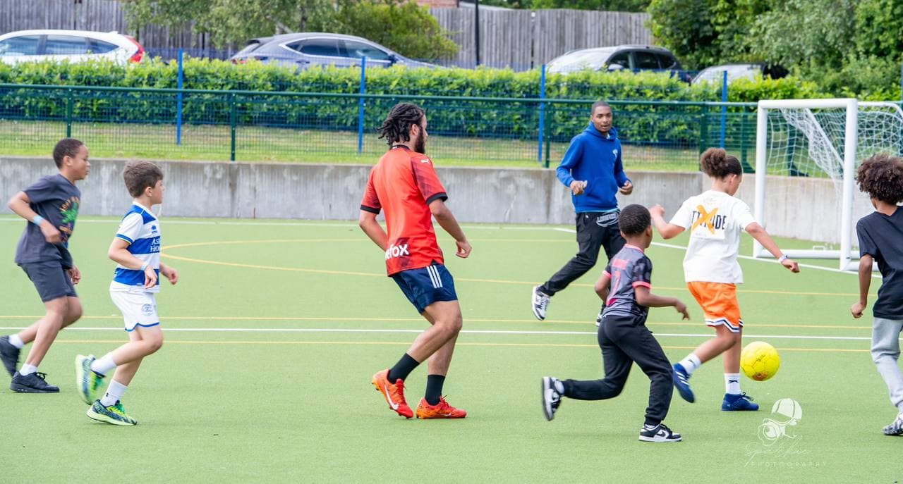 Children and mentors playing football at Roots & Wings 2024