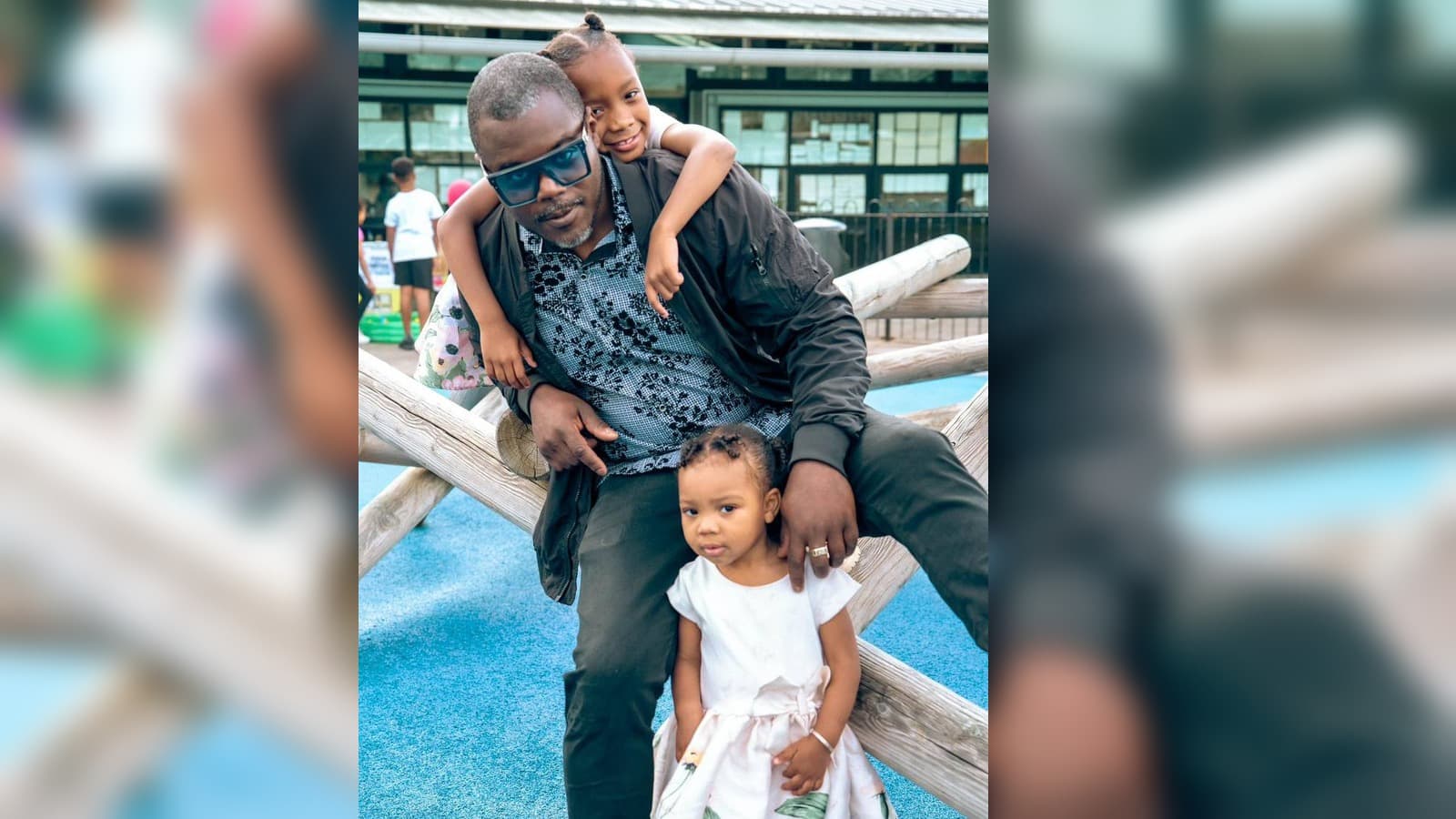Father with two daughters on a blue playground for the Tree of Hope