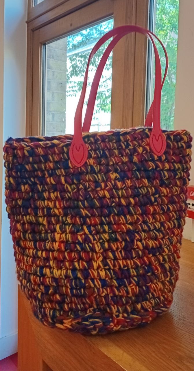 Crochet basket bag in autumn coloured yarn with bright red handles