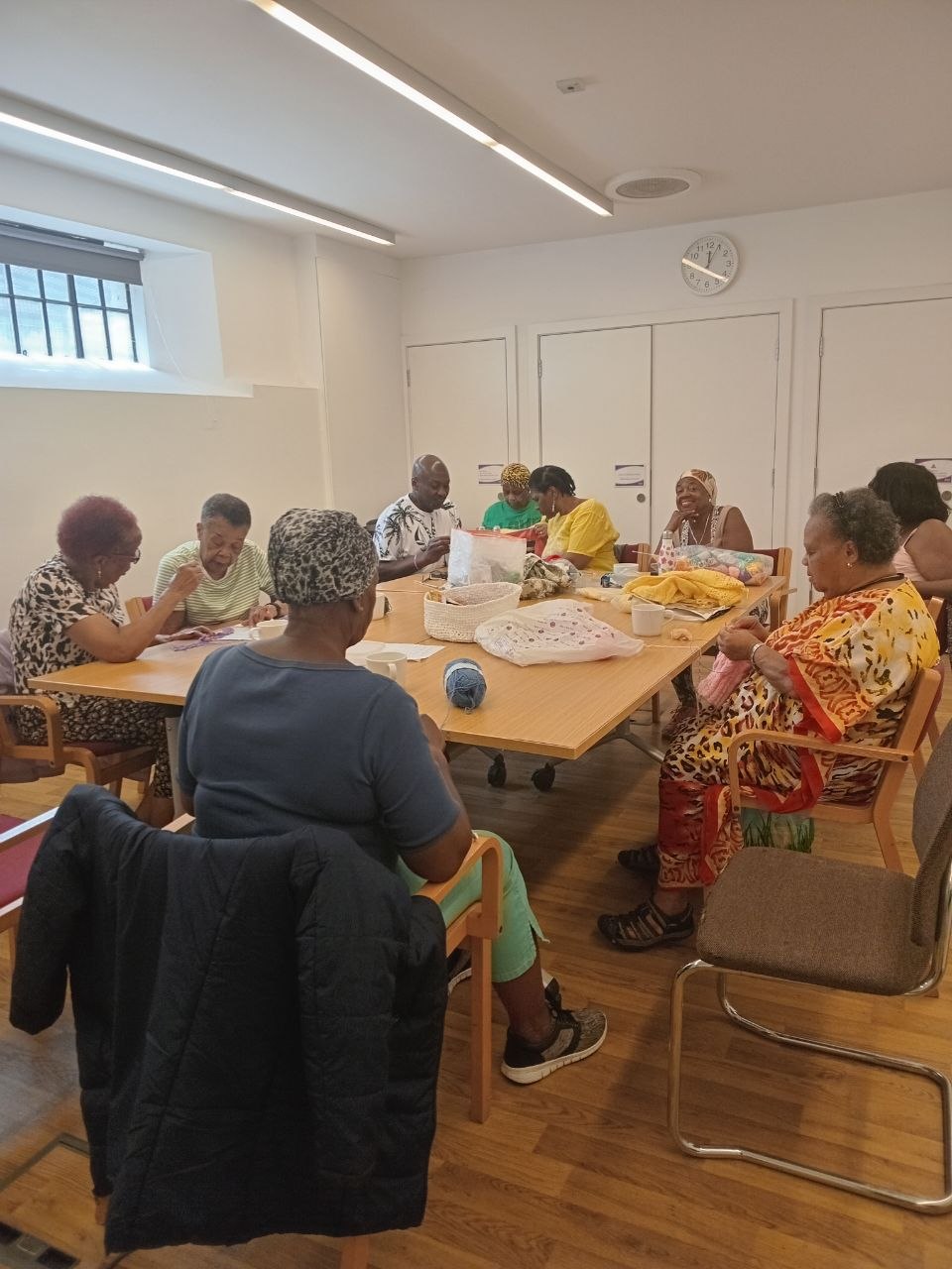 Stitch Craft N Knit community group gathered around a table knitting and crocheting together