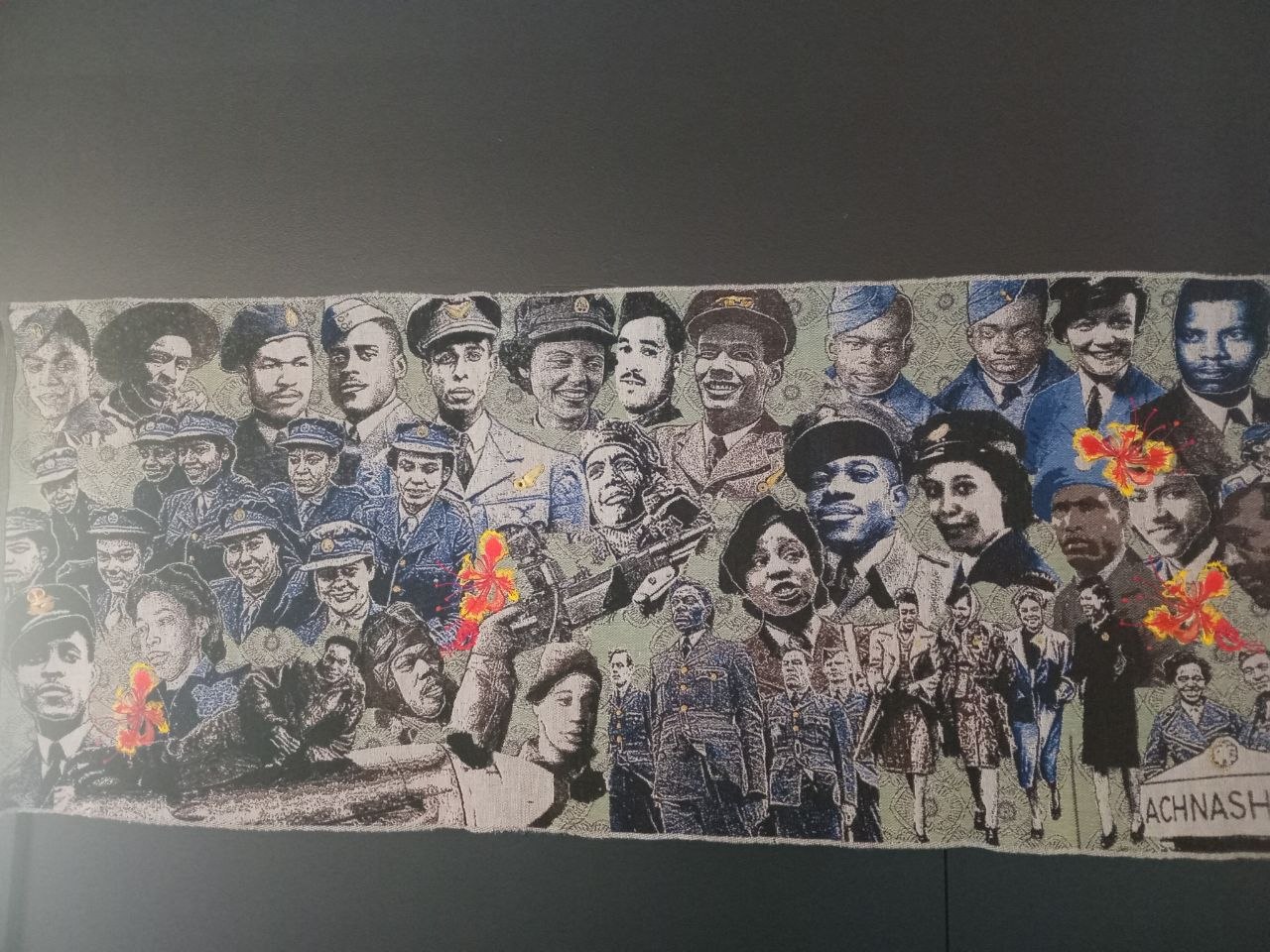 Textile display with portraits and floral details seen during a Stitch Craft N Knit outing